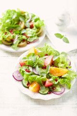 Salad with red and yellow Tomatoes and Pomegranate Seeds on bright wooden Background. Close up.