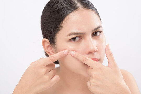 portrait of young beautiful woman is checking her skin and popping pimple over white background studio