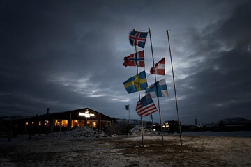 various flags of the Nordic countries are flying on the flagpole in wind against the background of the night sky in the clouds. Dramatic landscape - obrazy, fototapety, plakaty