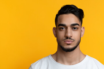 Attractive bearded arabic guy posing on yellow