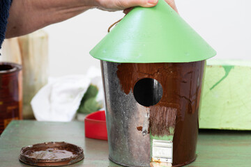 Persona pinta una pajarera de metal galvanizado