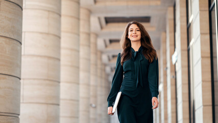 Obraz premium confident business woman brunette in a formal dress goes to work in the office in the bank
