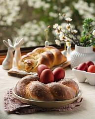 Obraz na płótnie Canvas Easter traditional bread, austrian ostern zopf, greek tsoureki and red eggs on a table with linen tablecloth with spring window view, still life
