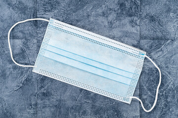 Covid-19 Home Preparation Kit - a single surgical mask on a blue coloured slate tiled background.