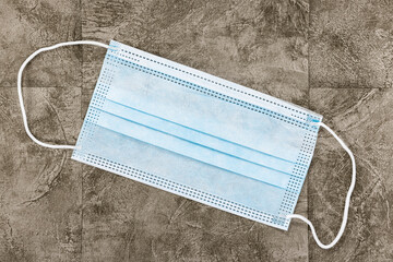 Covid-19 Home Preparation Kit - a single surgical mask on a warm coloured slate tiled background.