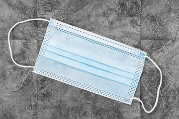 Covid-19 Home Preparation Kit - a single surgical mask on a grey coloured slate tiled background.