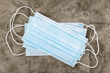 Covid-19 Home Preparation Kit - multiple surgical masks on a warm coloured slate tiled background.