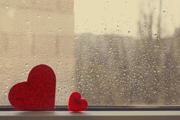 Two red hearts on a wet window in raindrops. Vintage.