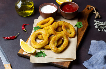 Fried squid rings with two sauces, lemon and herbs. Fast food. Appetizer.