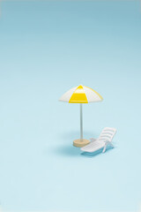 Travel concept. Sun lounger, yellow umbrella on a blue background.