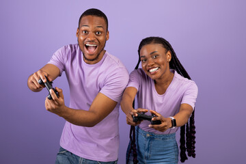 Excited African American couple playing video games together with joysticks
