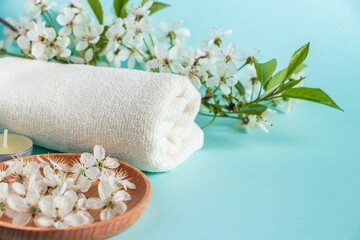 Aromatherapy wellness concept. Spa and relaxation accessories on blue background. Aromatic oil, towel, candle and flowers. Organic skin care product.