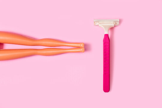 M&aacute;quina de afeitar desechable para mujeres junto a unas piernas de mu&ntilde;ecas sobre un fondo rosa pastel. Vista superior. Copy space. Concepto: Eliminaci&oacute;n del vello no deseado, cuidado corporal femenino