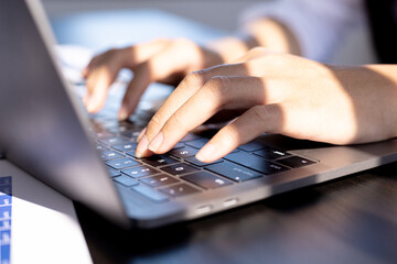 A business woman working in a private room, She is typing on a laptop keyboard, She uses a messenger to chat with a partner. Concept of using technology in communication.