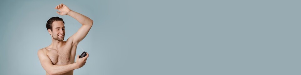 Fototapeta premium Handsome smiling nude man spraying deodorant