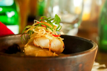 Closeup of garnished fish soup dish in a bowl served at an Indonesian restaurant