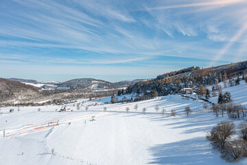 Aerial view shows western located vacation area in Willingen Upland. Snow covers mountainous...