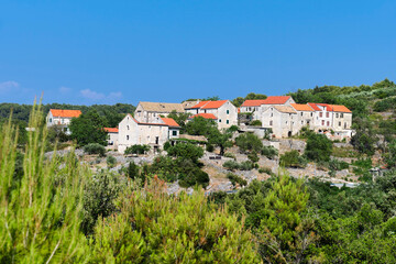 Fototapeta na wymiar Old village in mountains of Hvar island in Croatia on old mountain road between coastal towns. Old stone cottage houses under red tile roofs.