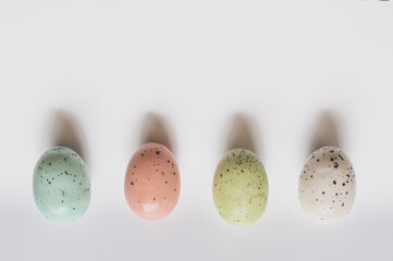 Four colored speckled eggs on white background - obrazy, fototapety, plakaty