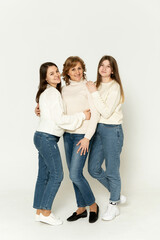 three girls stand on a white background in the studio and look at the camera. group portrait. mother with daughters on a white background.