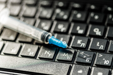 a disposable syringe lies on the laptop keyboard. online drug trafficking