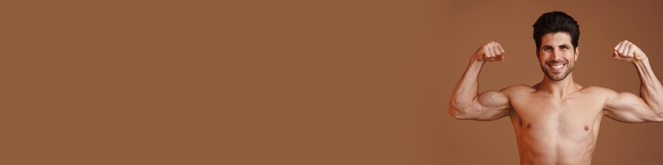 Fototapeta premium Shirtless happy man smiling and showing his biceps at camera