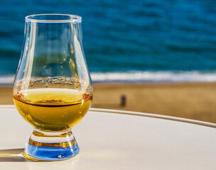 Exclusive single malt whiskey in a tasting glass with a beautiful view of the sea on a sunny day