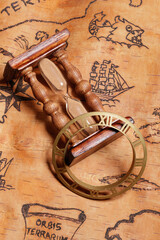 An hourglass and clock face lying on the order of antique nautical chart depicting sailing ships.