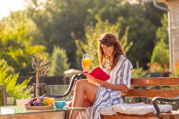 Woman drinking orange juice and reading a book