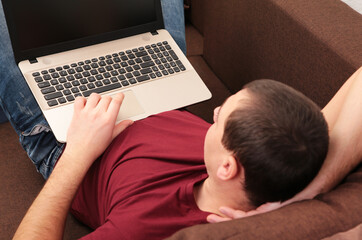 Businessman working at home with a laptop on sofa.