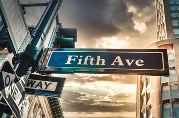 Fifth Ave 5th Ave, New York City sign, view from low angle with sunset and empire state building in...