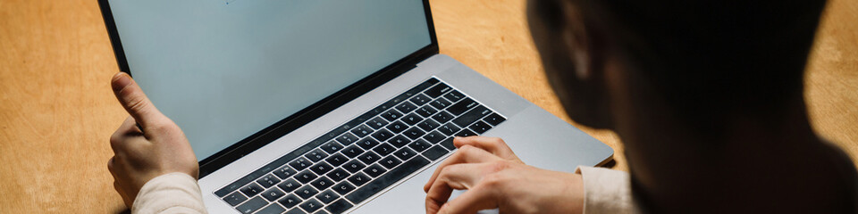 Back view of a mid aged brunette man looking at laptop