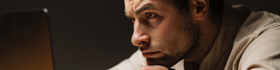 Obraz premium Tired bored mid aged brunette man looking at laptop