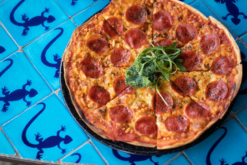 Pizza de peperoni sobre mesa azul 