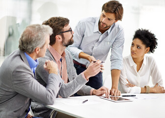 Hard working office pros. Shot of a group of young professionals working at a desk in an office.