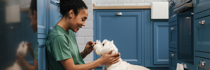 Smiling mid aged african woman playing with her dog
