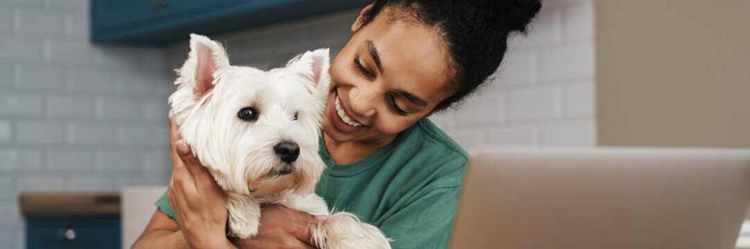 Smiling mid aged african woman sitting at the table indoors
