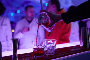 Alcoholic drinks at the bar. Bartender's hands in the process of making drinks.