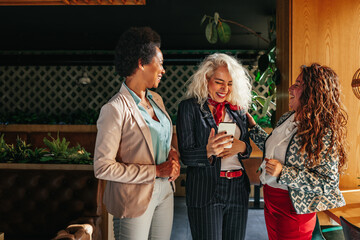 Three diverse women using mobile phone together