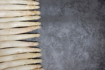 Fresh white asparagus on rustically stony background with empty tag 
