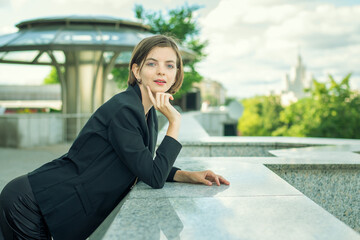 A young woman in a business black suit in town.