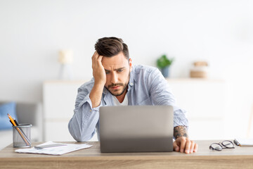 Freelance stress. Male freelancer tired after work on laptop at home, having problems with project,...