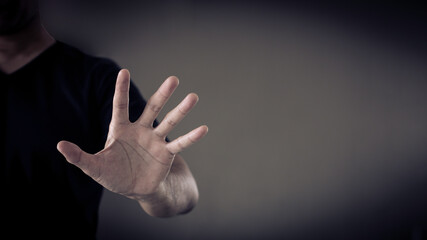 man showing stop sign palm, stop domestic violence concept, on copy space, black-gray background