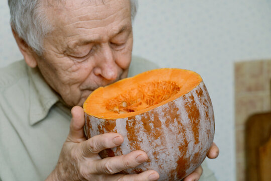 Senior Man Smelling Cut Pumpkin