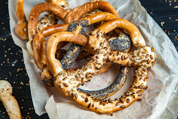 Fresh prepared homemade soft pretzels. Different types of baked pretzels with seeds on a black background