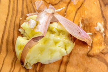 Crushed garlic clove in a sandal-wood cutting board