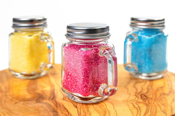 Yellow, red, and turquoise confectionary sugar in mason jars.