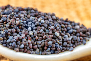 Macro of poppy seeds in a small white spoon