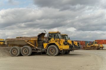An articulated dump truck waiting to be repaired stands near the containers at the gold mine site.