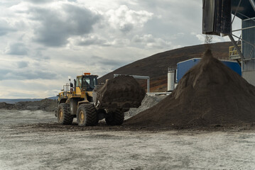 A loader with a full bucket stands near the filtration shop waiting to start loading.